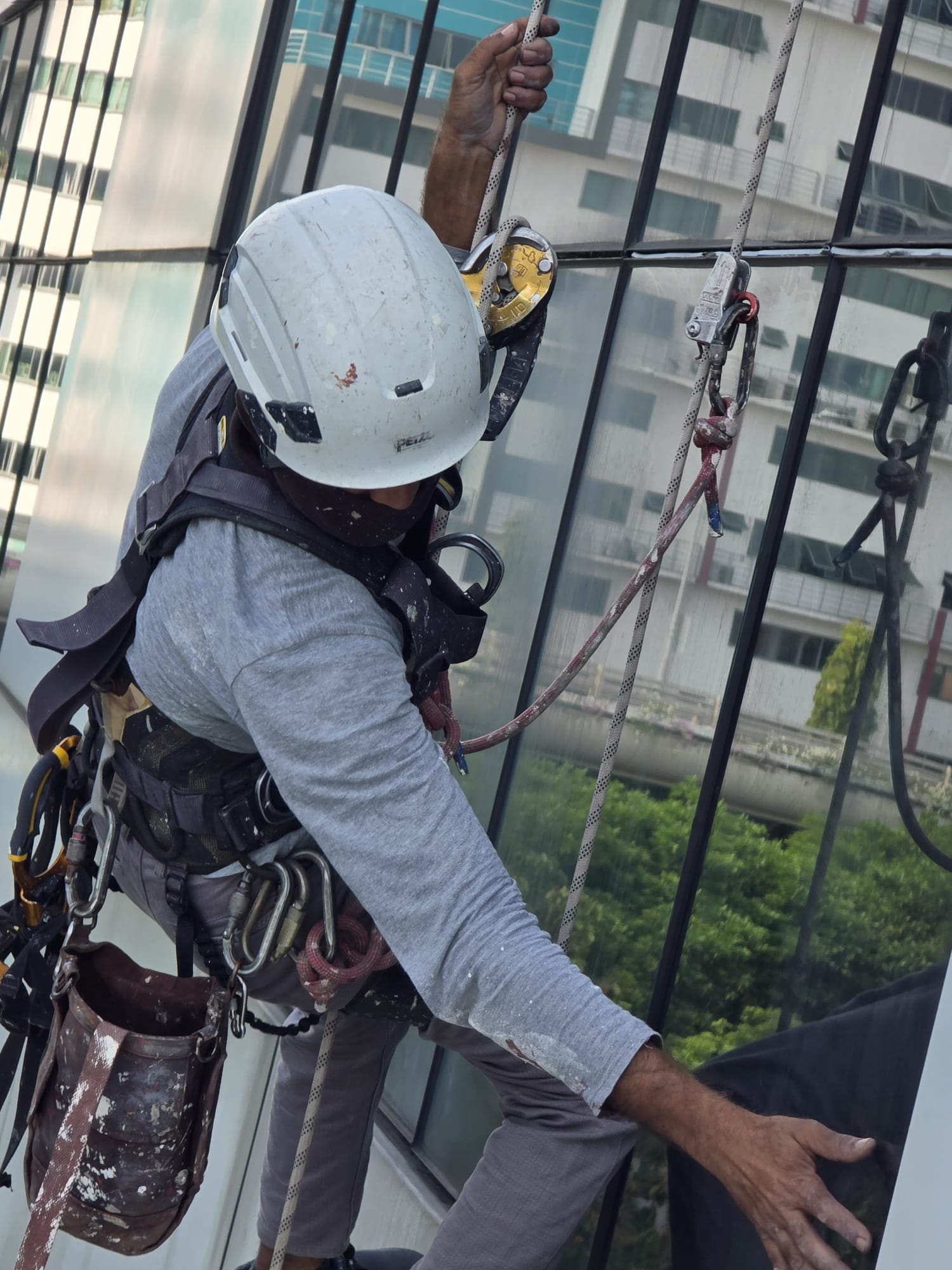 Rope-access façade inspector working across a Singapore high-rise curtain wall